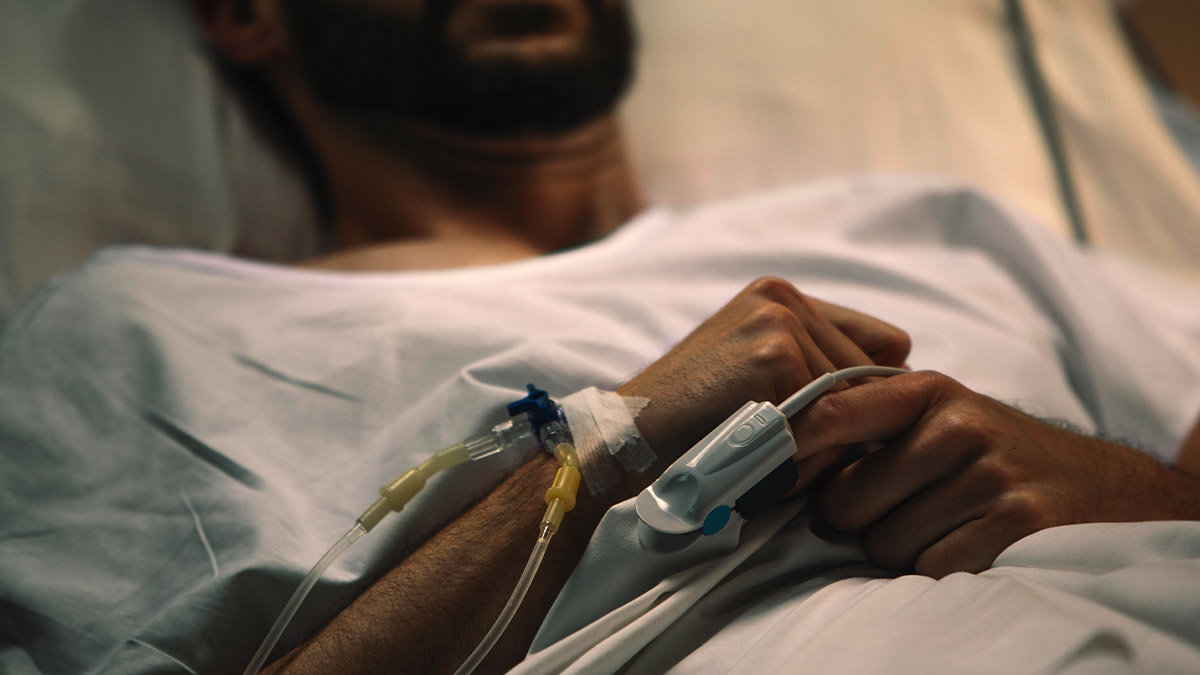 Paciente internado em ambiente hospitalar, com acesso venoso no braço, durante tratamento de saúde