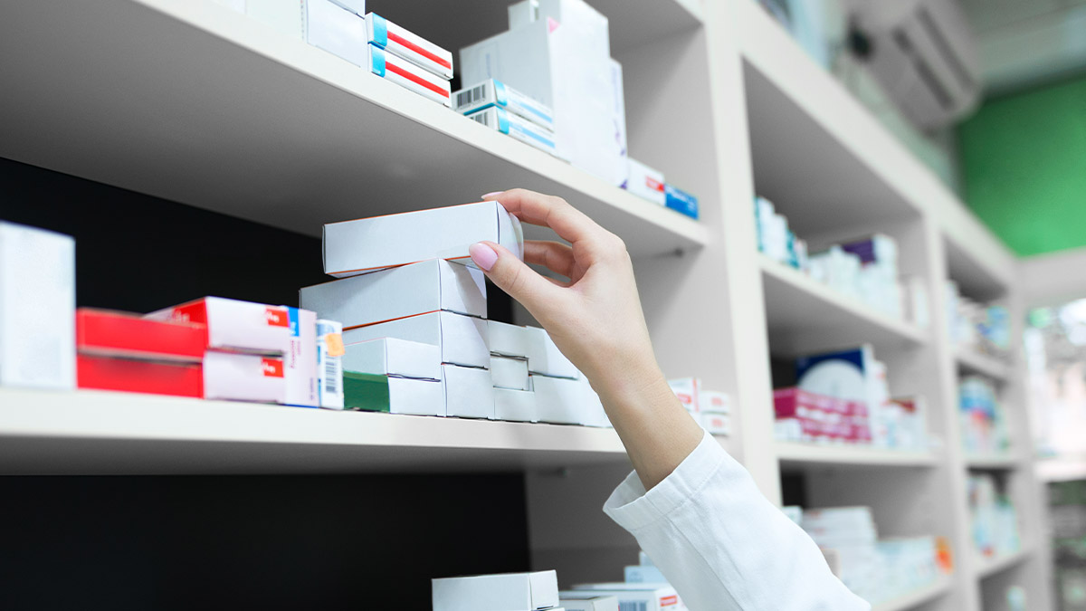 farmacêutica organizando caixas de medicamento rituximabe em prateleira de farmácia